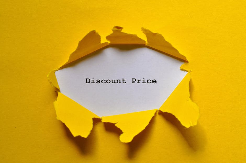A close-up view of a yellow paper surface with a large tear in the centre, revealing a white paper beneath with the words 'Discount Price' printed in black. The torn yellow paper has jagged edges around the opening, suggesting it was deliberately ripped to expose the message. The surface appears smooth, and the lighting creates subtle shadows around the torn edges, emphasizing the disruption in the paper. This image may metaphorically relate to cost considerations in home relocation or moving services, highlighting the importance of transparent pricing in the removals process, as offered by Man with Van Creekmouth for house removals and furniture transport in the Creekmouth area.